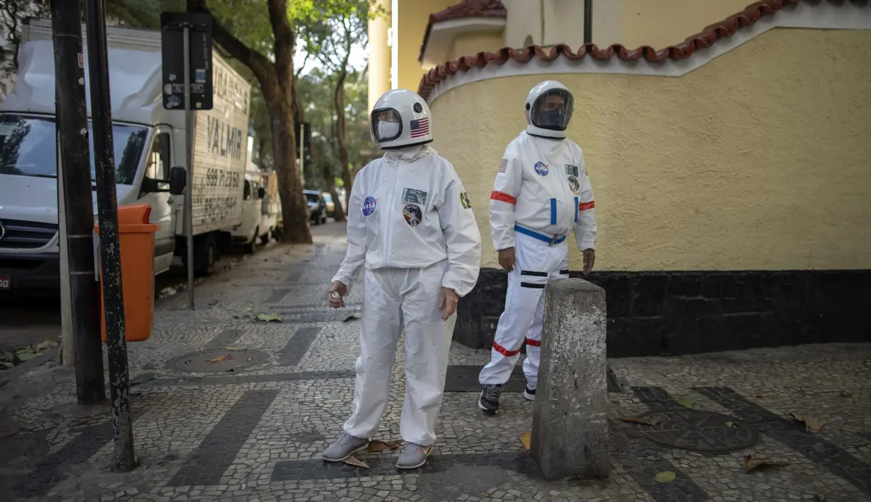 Akuntan Brasil Tercio Galdino (66) dan istrinya Alicea Galdino mengenakan pakaian pelindung mirip astronaut saat berjalan menuju Pantai Copacabana di Rio de Janeiro, Brasil, 12 Juli 2020. (Mauro Pimentel/AFP)