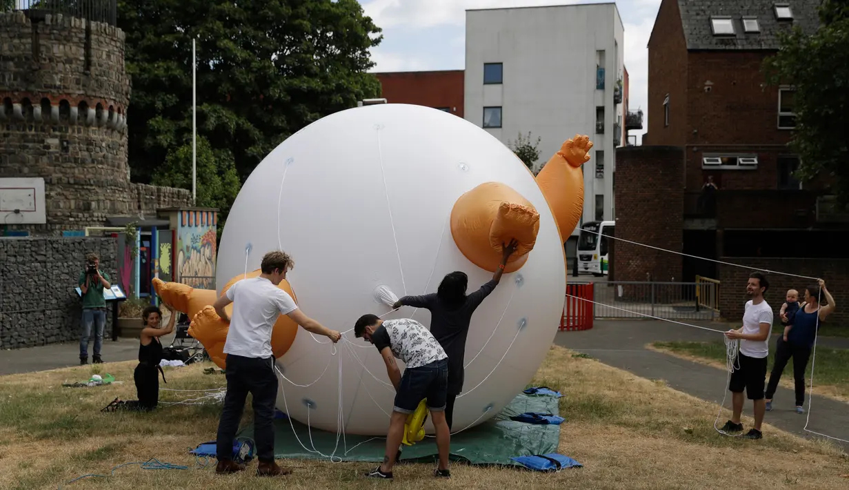 Aktivis mengembangkan balon berbentuk bayi Presiden AS Donald Trump di Bingfield Park, London, 10 Juli 2018. Balon bayi atau disebut Trump Baby itu dirancang sebagai pernyataan protes untuk Trump yang akan mengunjungi Inggris.  (AP /Matt Dunham)