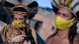 Angoho (kiri) dan suaminya, Hayo mengenakan masker di tengah Pandemi coronavirus novel COVID-19 di Vila Vitoria favela di pinggiran Belo Horizonte, negara bagian Minas Gerais, Brasil (8/7/2020). Angoho dan saudara-saudaranya telah diusir dua kali dari tanah mereka. (AFP/Douglas Magno)