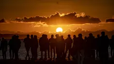 Orang-orang berkumpul di Pantai Selatan Chigasaki untuk menyaksikan matahari terbit pada Hari Tahun Baru di Prefektur Kanagawa, barat daya Tokyo (1/1/2021). Berburu matahari terbit di awal tahun tentu bisa menjadi salah satu aktivitas seru saat merayakan pergantian tahun. (AFP/Philip Fong)