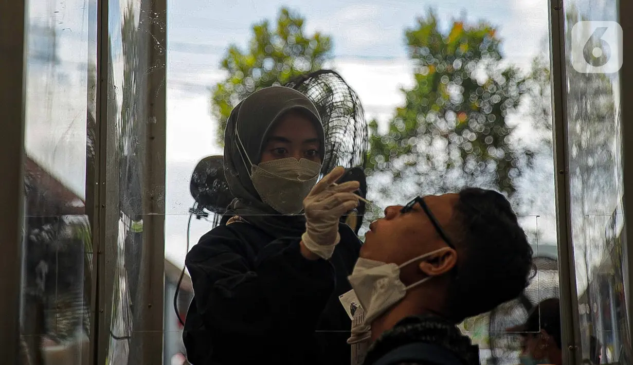 Calon penumpang menjalani tes swab PCR di Stasiun Pasar Senen, Jakarta, Jumat (24/12/2021). Mulai hari ini, penumpang kereta wajib menunjukkan hasil negatif tes PCR. (Liputan6.com/Faizal Fanani)