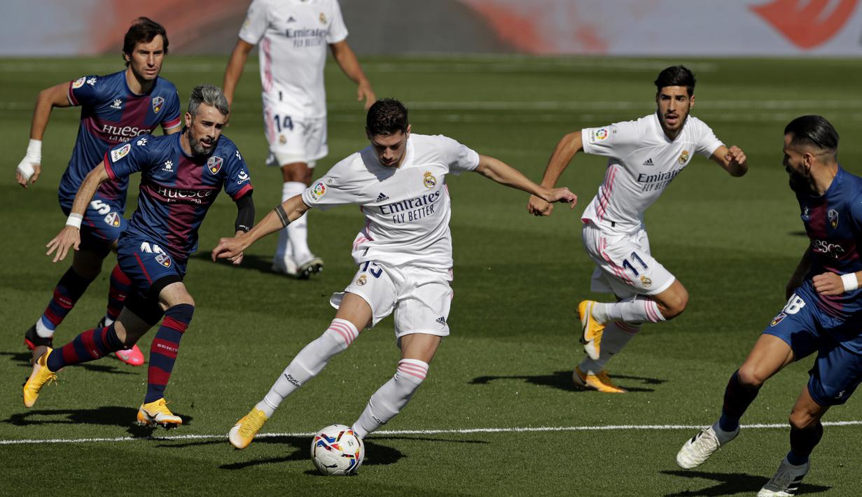 Gelandang Real Madrid, Federico Valverde, berusaha melewati pemain Huesca pada laga lanjutan Liga Spanyol di Stadion Alfredo Di Stefano, Sabtu (31/10/2020) malam WIB. Real Madrid menang 4-1 atas Huesca. (AP Photo/Manu Fernandez)