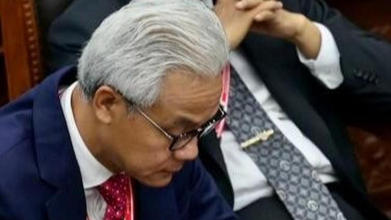 Ganjar juga sempat sibuk dengan ponselnya ketika sidang putusan tersebut sedang berlangsung. Sementara Mahfud duduk bersandar di kursi sambil mengangkat kedua tangannya ke depan bibirnya. Foto: AFP