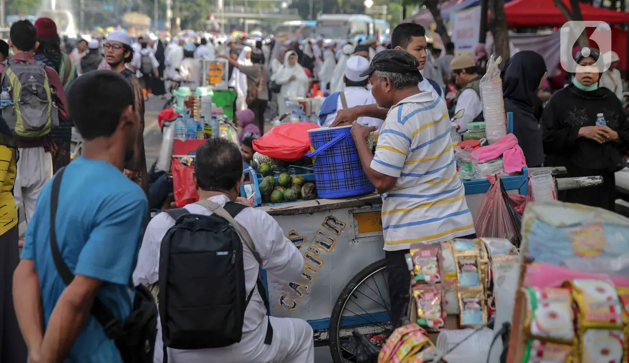 Pedagang minuman melayani pembeli saat berjualan di tengah aksi reuni 212, sekitaran Jalan Medan Merdeka Barat, Jakarta, Senin (2/12/2019). Sejumlah PKL meraup untung dengan berjualan di tengah ribuan massa Persaudaraan Alumni 212 yang mengikuti reuni di Monas. (Liputan6.com/Faizal Fanani)