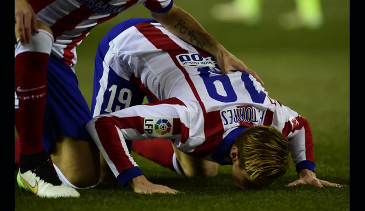 Fernando Torres merayakan golnya ke gawang Barcelona dengan mencium rumput stadion. Barcelona keluar sebagai pemenang dengan skor 3-2, Spanyol, Kamis (29/1/2015). (AFP Photo)