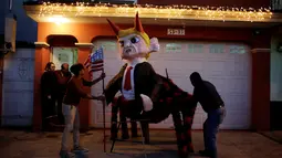 Sejumlah pria memperbaiki pinata yang berbentuk karakter Donald Trump sebelum perayaan tradisional, Pembakaran Iblis di Guatemala City, Guatemala (7/12). Pinata tersebut berbentuk Trump yang memilki tanduk dan berkaki laba-laba. (Reuters/Luis Echeverria)