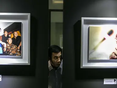 Pengunjung mengintip dari celah-celah pada pameran Satu Dekade Haul Presiden ke IV Republik Indonesia KH Abdurrahman Wahid atau Gus Dur di Kantor DPP PKB, Jakarta, Rabu (15/1/2020). Pameran sekaligus lomba foto ini diikuti oleh puluhan fotografer dari seluruh Indonesia. (Liputan6.com/Faizal Fanani)