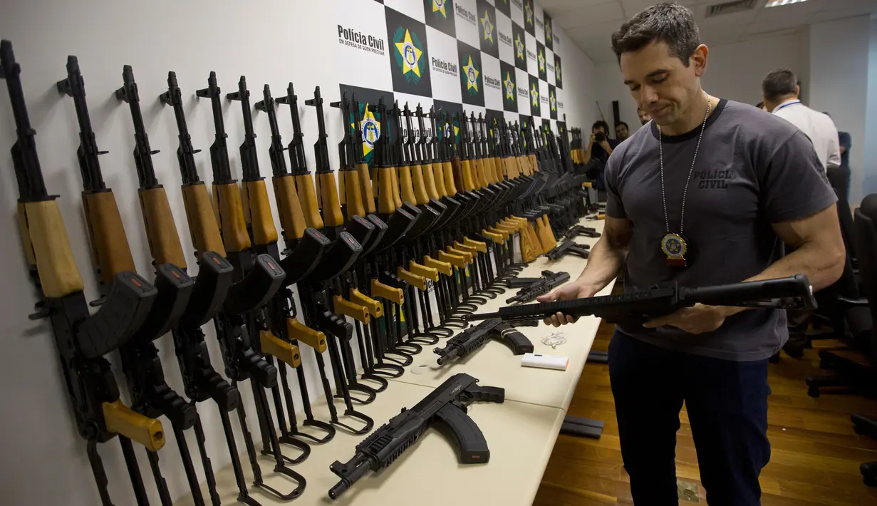 Polisi Brasil memegang senapan serbu yang disita saat konferensi pers di Rio de Janeiro, 1 Juni 2017.  Kepolian Rio de Janeiro memperkirakan senjata itu akan dijual seharga USD1,5 juta atau sekitar Rp19,9 miliar di pasar Brasil (AP Photo/Silvia Izquierdo)
