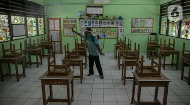Seorang guru mendisinfeksi kelas yang akan digunakan di SDN Kenari 08, Jakarta, Selasa (6/4/2021). Pemerintah Provinsi DKI Jakarta akan melakukan uji coba pembelajaran tatap muka terbatas di 100 sekolah mulai 7 April hingga 29 April 2021. (Liputan6.com/Faizal Fanani)