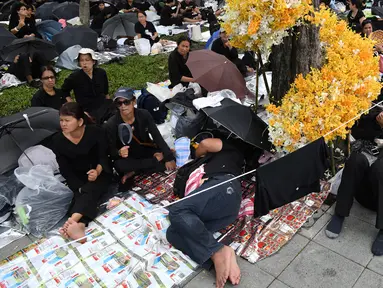 Warga mengenakan pakaian hitam menunggu pemakaman mendiang Raja Thailand Bhumibol Adulyadej di Bangkok (25/10). Prosesi kremasi penguasa monarki terlama Thailand itu baru akan dilakukan pada hari Kamis (26/10/2017). (AFP Photo/Roberto Schmidt)