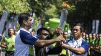 Pevoli legendaris Indonesia, Pascal Wilmar, menyerahkan obor Asian Games XVIII saat pawai di Denpasar, Bali, Selasa (24/7/2018). Sebanyak 53 kota di Indonesia akan dilalui oleh obor Asian Games. (Bola.com/Vitalis Yogi Trisna)