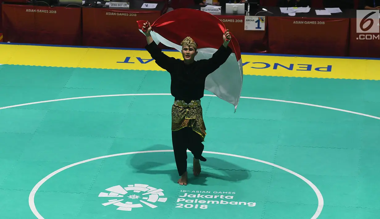 Pesilat Indonesia Sugianto membawa bendera merah putih usai meraih medali emas dalam babak final tunggal putra pencak silat seni Asian Games 2018 di Padepokan Pencak Silat Taman Mini Indonesia Indah (TMII), Jakarta, Rabu (29/8). (Merdeka.com/ Imam Buhori)