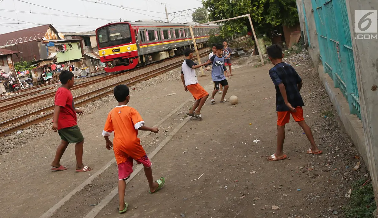 Kereta melintas di kawasan Kemayoran, Jakarta, Senin (24/7). Minimnya lahan bermain menyebabkan anak-anak terpaksa bermain di lokasi tersebut, meskipun berbahaya bagi keselamatan. (Liputan6.com/Immanuel Antonius)