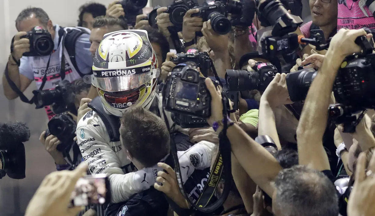 Pebalap Mercedes, Lewis Hamilton merayakan kemenangan bersama tim mekanik pada balapan F1 GP Singapura di  Marina Bay City Circuit, (17/9/2017). Hamilton kini memiliki total poin 263. (AP/Wong Maye-E)