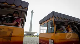 Para pengunjung Monas tampak menikmati pemandangan sekitar kawasan Monas dengan menaiki mobil gandeng, Jakarta, Kamis (14/5/2015). (Liputan6.com/Faizal Fanani)