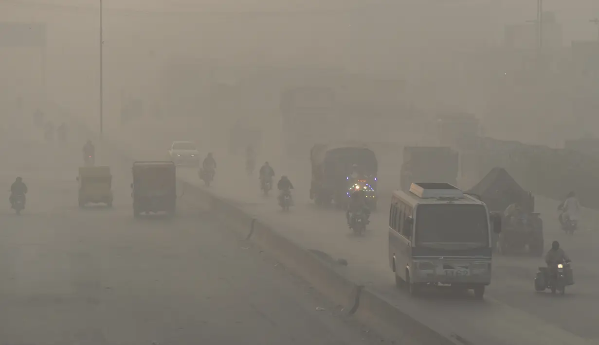 Pengendara kendaraan melintas di tengah kondisi kabut asap di Lahore, Pakistan, Senin (8/11/2021). Lahore menjadi salah satu kota paling tercemar di dunia. (Arif ALI/AFP)