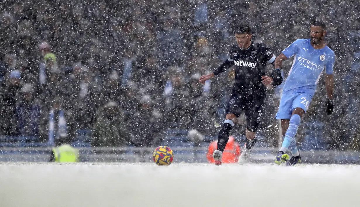 Gelandang Manchester City, Riyad Mahrez mengumpan bola dari kawalan pemain West Ham United, Aaron Cresswell pada pertandingan Liga Inggris di stadion Etihad, Inggris, Minggu (28/11/2021). Hasil Ini membawa Manchester City salip Liverpool di posisi dua klasemen Liga Inggris. (AP Photo/Scott Heppell)