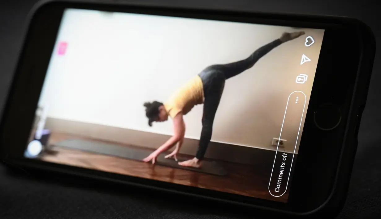 Seorang guru yoga mengajar kelas live yang disiarkan di akun Instagram-nya pada hari kesembilan belas selama lockdown yang bertujuan untuk membatasi penyebaran infeksi COVID-19 yang disebabkan oleh coronavirus novel di Paris, Prancis (4/4/2020). (AFP/Philippe Lopez)