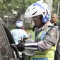 Petugas menilang pengendara mobil yang melanggar aturan pembatasan kendaraan sistem ganjil genap di kawasan Sudirman, Jakarta, Selasa (30/8). Hari ini resmi diberlakukan denda bagi pelanggar aturan sistem ganjil genap. (Liputan6.com/Yoppy Renato)