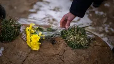 Seorang pria meletakkan bunga di makam seorang kerabatnya dalam upacara peringatan satu tahun dimulainya perang Rusia-Ukraina, di sebuah pemakaman di Bucha, Ukraina, Jumat, 24 Februari 2023. (AP Photo/Emilio Morenatti)