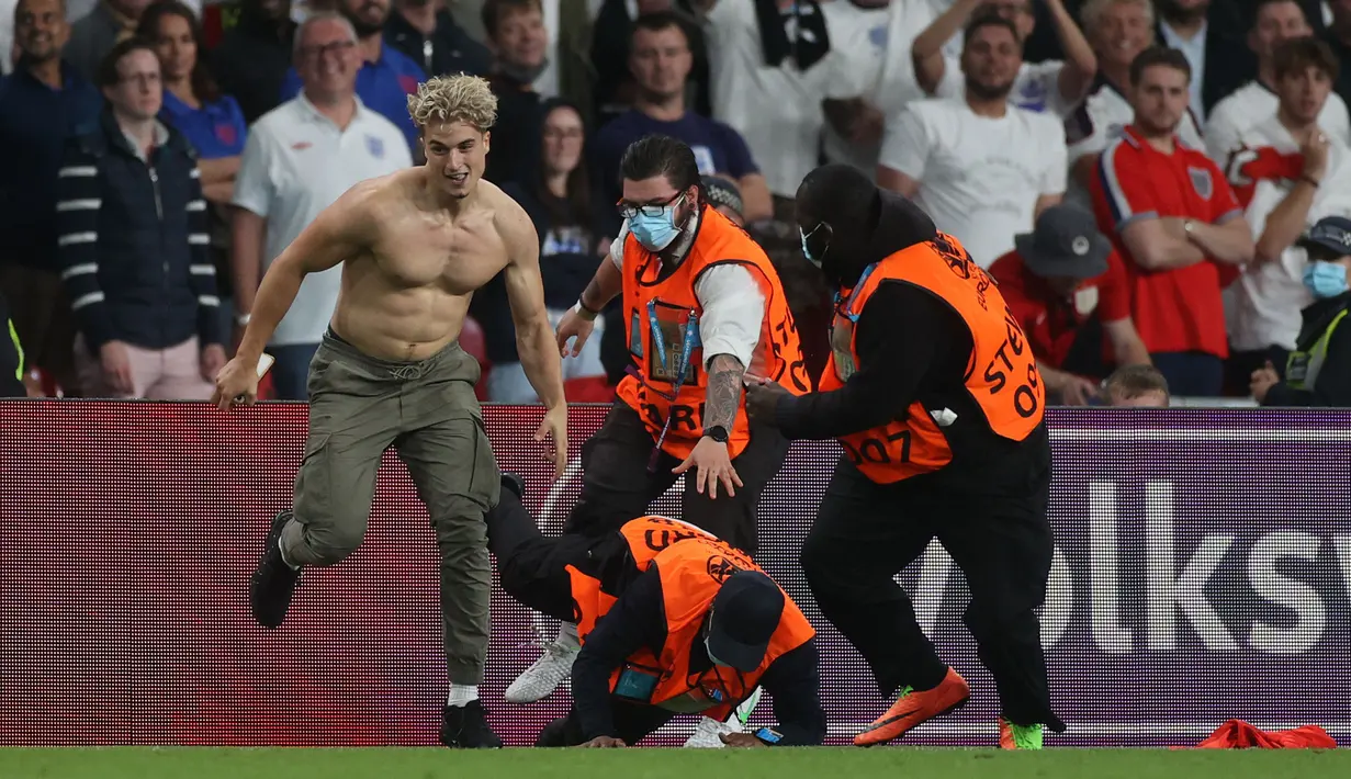 Seorang petugas keamanan jatuh di lapangan saat mengejar penyusup lapangan selama pertandingan sepak bola Final UEFA EURO 2020 antara Italia melawan Inggris di Stadion Wembley, London, Inggris pada 11 Juli 2021. (AFP/Pool/Carl Recine)