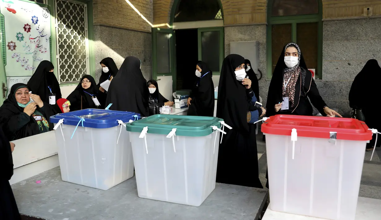 Pejabat pemilu Iran menyiapkan kotak suara di sebuah tempat pemungutan suara di Teheran, Iran, Jumat (18/6/2021). Warga Iran mulai memberikan suaranya dalam pemilihan presiden. (AP Photo/Ebrahim Noroozi)