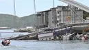 Tim penyelamat menggunakan kapal kecil bersiap mengevakuasi dalam pekerjaan kapal di lokasi jembatan yang ambruk di pelabuhan Nanfangao di kota Suao (1/10/2019). Tiga perahu nelayan yang tertimpa serta kendaraan di atas jembatan yang rusak, termasuk truk tangki. (AFP Photo/Sam Yeh)