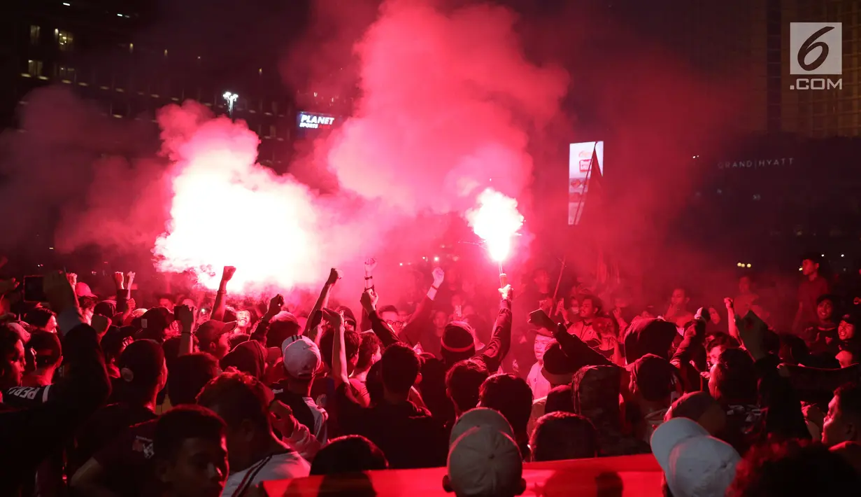 Suporter tim Macan Kemayoran menyalakan flare saat merayakan gelar juara Go-Jek Liga 1 Indonesia 2018 bersama Bukalapak yang diraih Persija di kawasan Bundaran HI, Jakarta, Minggu (9/12). Persija juara dengan 62 poin. (Liputan6.com/Helmi Fithriansyah)