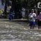 Warga melintasi genangan air yang merendam jalan di kawasan Kampung Makasar, Jakarta Timur, Senin (7/7/2025). (Liputan6.com/Herman Zakharia)