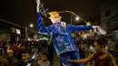 Warga berkumpul didekat patung Donald Trump sebelum dibakar saat perayaan pembakaran Yudas di Mexico City, Meksiko (15/4). Patung tersebut diberi pakaian warna biru, dasi merah dan rambut pirang yang menjadi ciri khas Trump. (AP Photo/Rebecca Blackwell)