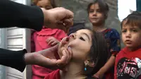 Tenaga kesehatan (kiri) memberikan vaksin polio kepada seorang anak selama kampanye vaksinasi di kawasan tua Kabul, Afghanistan pada 8 November 2021. Vaksinasi tersebut merupakan yang pertama sejak Taliban berkuasa di Afghanistan. (WAKIL KOHSAR / AFP)