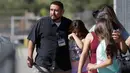 Camilo Rocha (kiri) menenangkan putrinya setelah insiden penembakan di Sekolah Dasar North Park, San Bernardino di California, Senin (10/4). Polisi menyebut aksi itu sebagai pembunuhan yang diikuti bunuh diri sang pelaku. (AP Photo/Jae C. Hong)