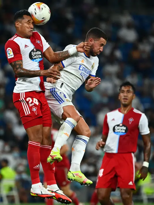 Pemain Celta Vigo Jeison Murillo (kiri) menyundul bola di samping pemain Real Madrid Eden Hazard pada pertandingan Liga Spanyol di Stadion Santiago Bernabeu, Madrid, Spanyol, 12 September 2021. Karim Benzema mencetak hattrick saat Real Madrid mengalahkan Celta Vigo 5-2. (GABRIEL BOUYS/AFP)