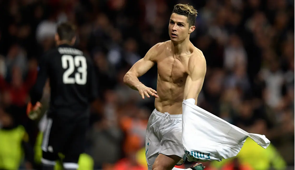 Striker Real Madrid Cristiano Ronaldo melepas jerseynya saat merayakan gol usai membobol gawang Juventus lewat tendangan penalti dalam petandingan Liga Champions di stadion Santiago Bernabeu, Madrid (11/4). (AFP Photo/Oscar Del Pozo)