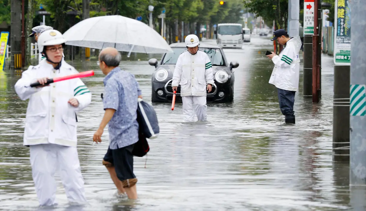 Petugas kepolisian mengatur jalan raya saat banjir merendam Saga, Jepang, Rabu (28/8/2019). Pejabat Badan Meteorologi Jepang, Yasushi Kajiwara memperingatkan warga yang tinggal di lokasi-lokasi rawan untuk segera angkat kaki tanpa menunggu peringatan lanjutan. (Takuto Kaneko/Kyodo News via AP)