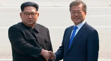 Pemimpin Korea Utara Kim Jong-un dan Presiden Korea Selatan Moon Jae-in berjabat tangan untuk memulai pertemuan bersejarah mereka di atas garis demarkasi Zona Demiliterisasi (DMZ), Panmunjom, Jumat (27/4). (Korea Broadcasting System via AP)