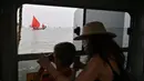 Wanita dan anak kecil melihat anggota asosiasi pelayaran budaya berlayar dalam acara Regatta Merah di Venesia, Italia, Minggu (20/6/2021). Acara ini untuk merayakan tradisi bahari Venesia kuno dan untuk meningkatkan kesadaran tentang keseimbangan antara kota dan laut. (MARCO BERTORELLO/AFP)