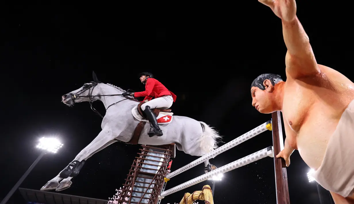 Atlet Swiss Martin Fuchs mengendarai Clooney 51 berkompetisi melewati patung pegulat sumo kecil dalam kualifikasi individu lompat berkuda selama Olimpiade Tokyo 2020 di Equestrian Park di Tokyo (3/8/2021). (AFP/Behrouz Mehri)