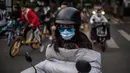 Seorang perempuan yang memakai masker untuk mengurangi risiko tertular virus corona COVID-19 bepergian dengan sepeda listrik selama jam sibuk di Beijing, China pada 14 Oktober 2020. (Photo by NICOLAS ASFOURI / AFP)