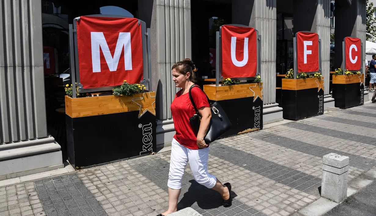 Seorang wanita berjalan melewati bendera yang menggambarkan klub Manchester United, di Skopje pada 8 Agustus 2017 menjelang pertandingan sepak bola UEFA Super Cup antara Real Madrid dan Manchester United. (AFP Photo/Armend Nimani)