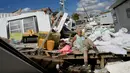 Kathy Hickey (70) dengan hati-hati memanjat trailer yang hancur saat dia mengambil jalan melalui puing-puing ke tempat dia dan suaminya Bruce di Pulau San Carlos, Pantai Fort Myers, Florida, Rabu (5/10/2022). Dampak dari badai ini membuat kerusakan pada infrastruktur listrik yang membutuhkan waktu satu bulan untuk pemulihannya. (AP Photo/Rebecca Blackwell)