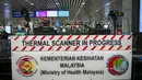 Petugas kesehatan memantau suhu tubuh penumpang yang tiba dengan 'thermal scanner' di Bandara Internasional Kuala Lumpur, Sepang, pada Selasa (21/1/2020). Pemerintah Malaysia mulai mengoperasikan alat pemindai suhu tubuh merespons penyebaran virus korona yang kian masif di China. (MOHD RASFAN/AFP)