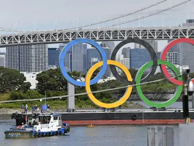 Para pekerja bersiap melepas cincin Olimpiade yang mengambang di air setelah Olimpiade Musim Panas 2020 berakhir pada 8 Agustus, di Tokyo, Rabu (11/8/2021).  Ajang yang digelar sejak 23 Juli itu akhirnya memastikan Kontingen Amerika Serikat (AS) menjadi juara umum. (Kyodo News via AP)
