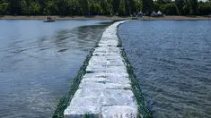 Warga memeriksa jembatan apung dari botol plastik yang ditempatkan di Danau Ada Ciganlija di Beograd, Serbia, Kamis, 27 Juli 2023. (AP Photo/Darko Vojinovic)