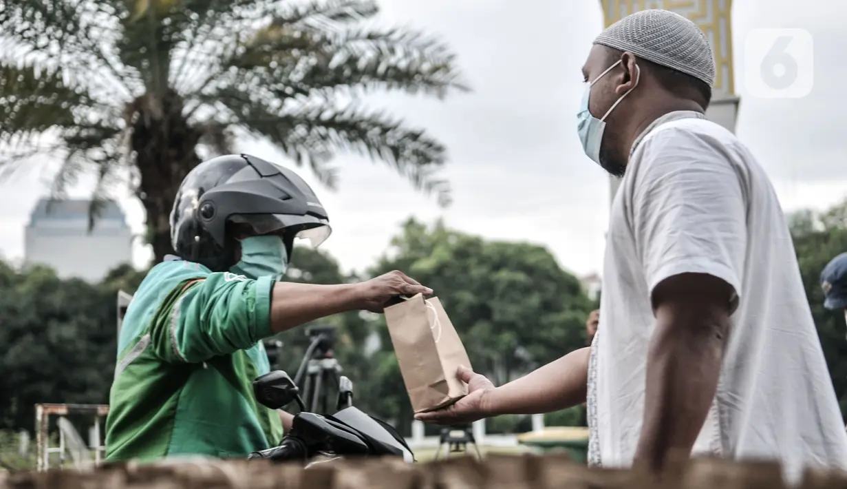 Petugas membagikan takjil kepada pengendara secara drive thru di Kompleks Masjid Al-Azhar, Jakarta, Selasa (13/4/2021). Pengelola Masjid Al-Azhar menyiapkan 500 bungkus takjil per hari yang dibagikan secara drive thru guna mencegah penyebaran COVID-19. (merdeka.com/Iqbal S. Nugroho)