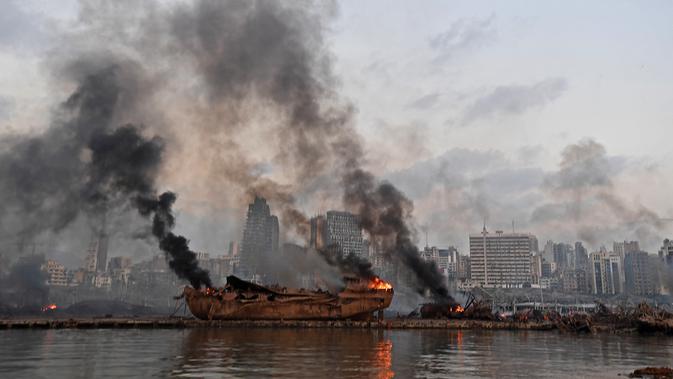 Sebuah kapal besar yang terbakar setelah ledakan besar di pelabuhan Kota Beirut, Lebanon (5/8/2020). Kapal besar tersebut terangkat ke daratan setelah dua ledakan besar menghantam Beirut pada Selasa (4/8/2020) lalu. (AFP Photo)