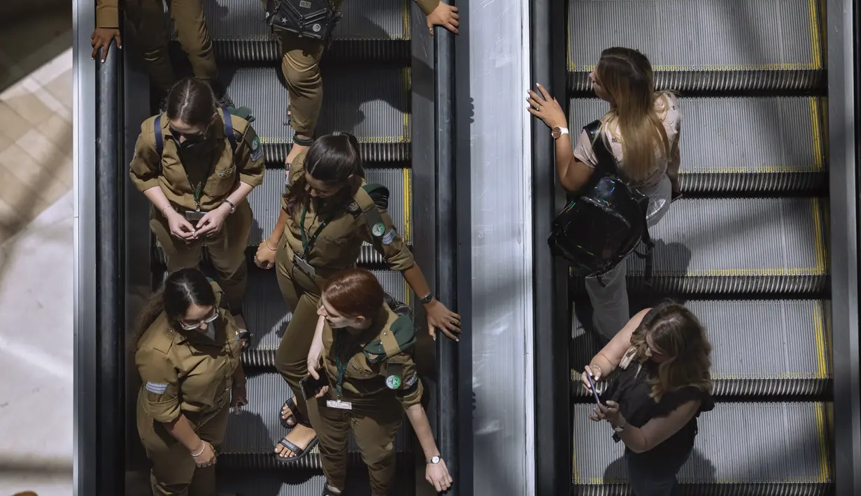Orang-orang menaiki eskalator di pusat perbelanjaan setelah aturan yang mewajibkan pemakaian masker di dalam ruangan dicabut, di Tel Aviv, Selasa (15/6/2021). Israel mencabut salah satu aturan virus corona terakhirnya pada Selasa setelah program vaksinasi dianggap sukses. (AP Photo/Oded Balilty)