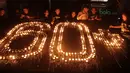 Pencinta lingkungan dan warga menyalakan lilin saat pemadaman lampu memperingati Earth Hour 2018 di Stadion Utama Gelora Bung Karno, Jakarta (24/3/2018). Salah satu tujuan Earth Hour 2018 adalah memperbaiki ekosistem Bumi. (Bola.com/Nick Hanoatubun)