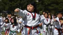 Seorang anak wanita unjuk kebolehan Taekwondo di luar gedung Majelis Nasional Korea Selatan di Seoul (21/5). Acara ini diharapkan untuk menetapkan new Guinness world record. (AFP Photo/Jung Yeon-je)