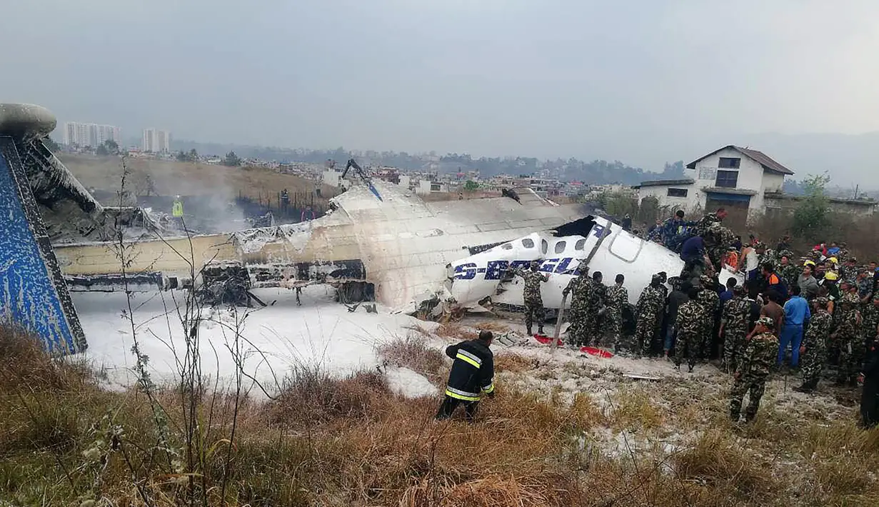 Suasana saat tim penyelamat berkumpul di sekitar puing pesawat yang jatuh di dekat Bandara Internasional Kathmandu, Nepal, Senin (12/3). Sebanyak 40 orang tewas dan 23 lainnya cedera. (Saroj BASNET/AFP)